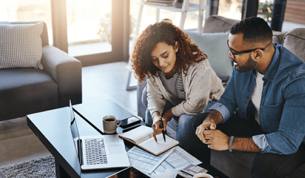 A man and woman go over their finances at the coffee table to decide if they should get a joint bank account.