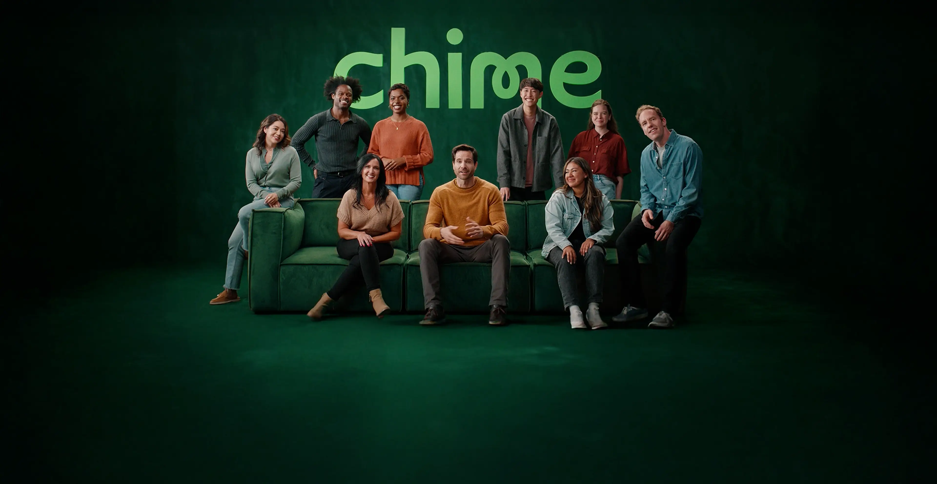 Nine different Chime members sitting and standing around a green couch with the Chime logo in the background.