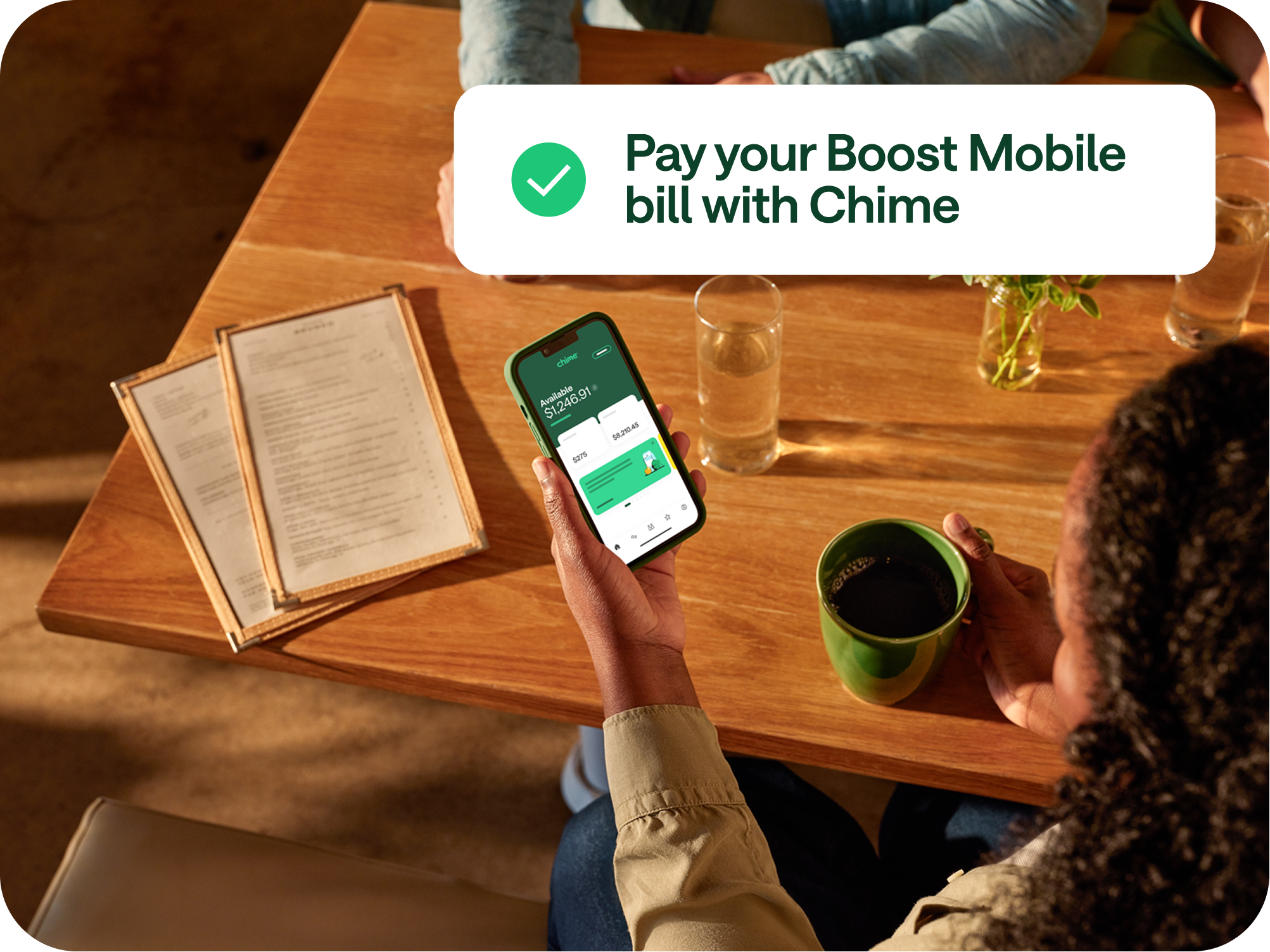 A person looking at the Chime app on their phone. There is a banner that says "Pay your Boost Mobile bill with Chime"