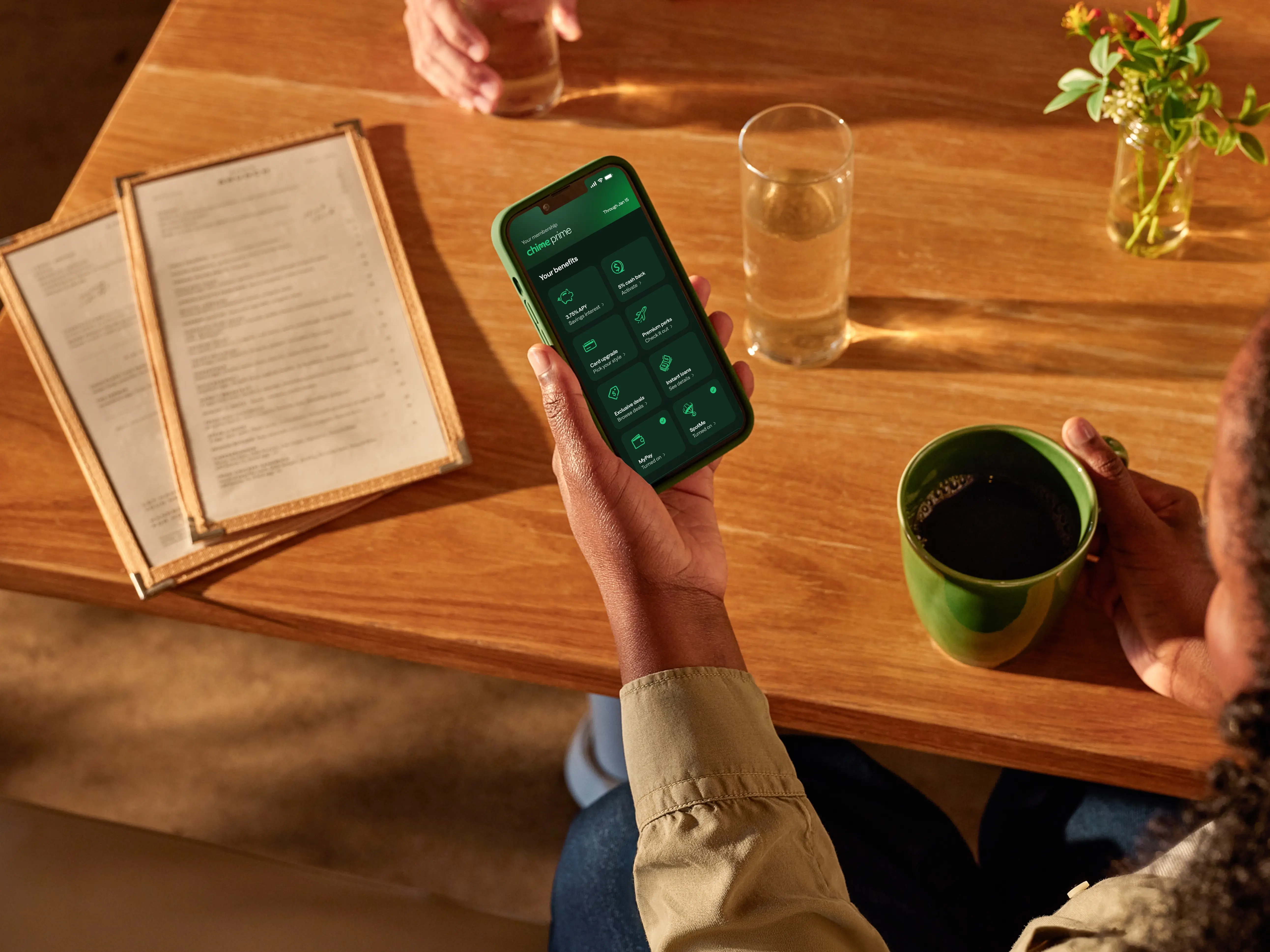 A hand holding a phone screen showing Chime Prime benefits.