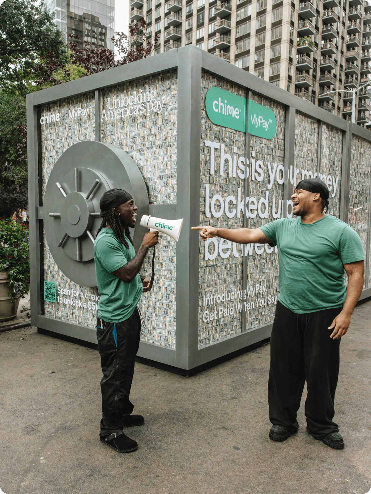 Kai and Fanum stand in front of the Chime MyPay Vault truck with a megaphone.