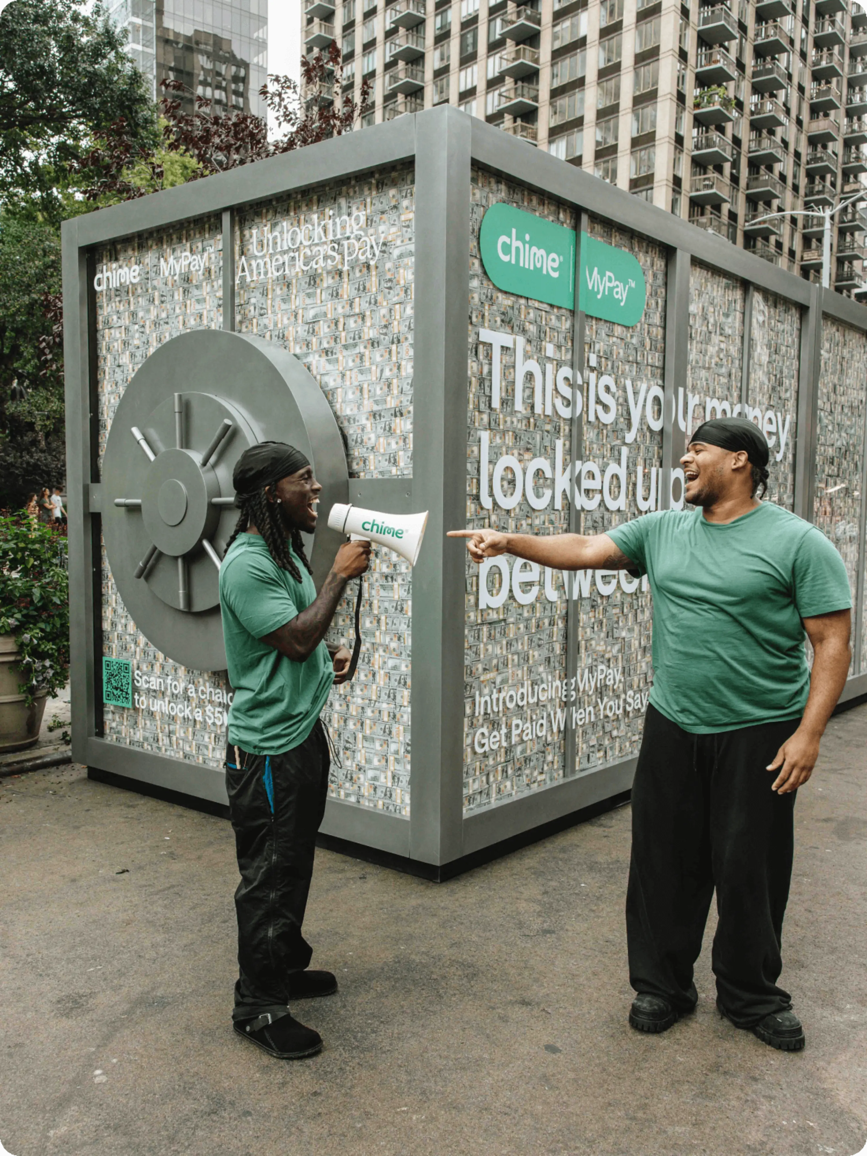 Kai and Fanum stand in front of the Chime MyPay Vault truck with a megaphone.