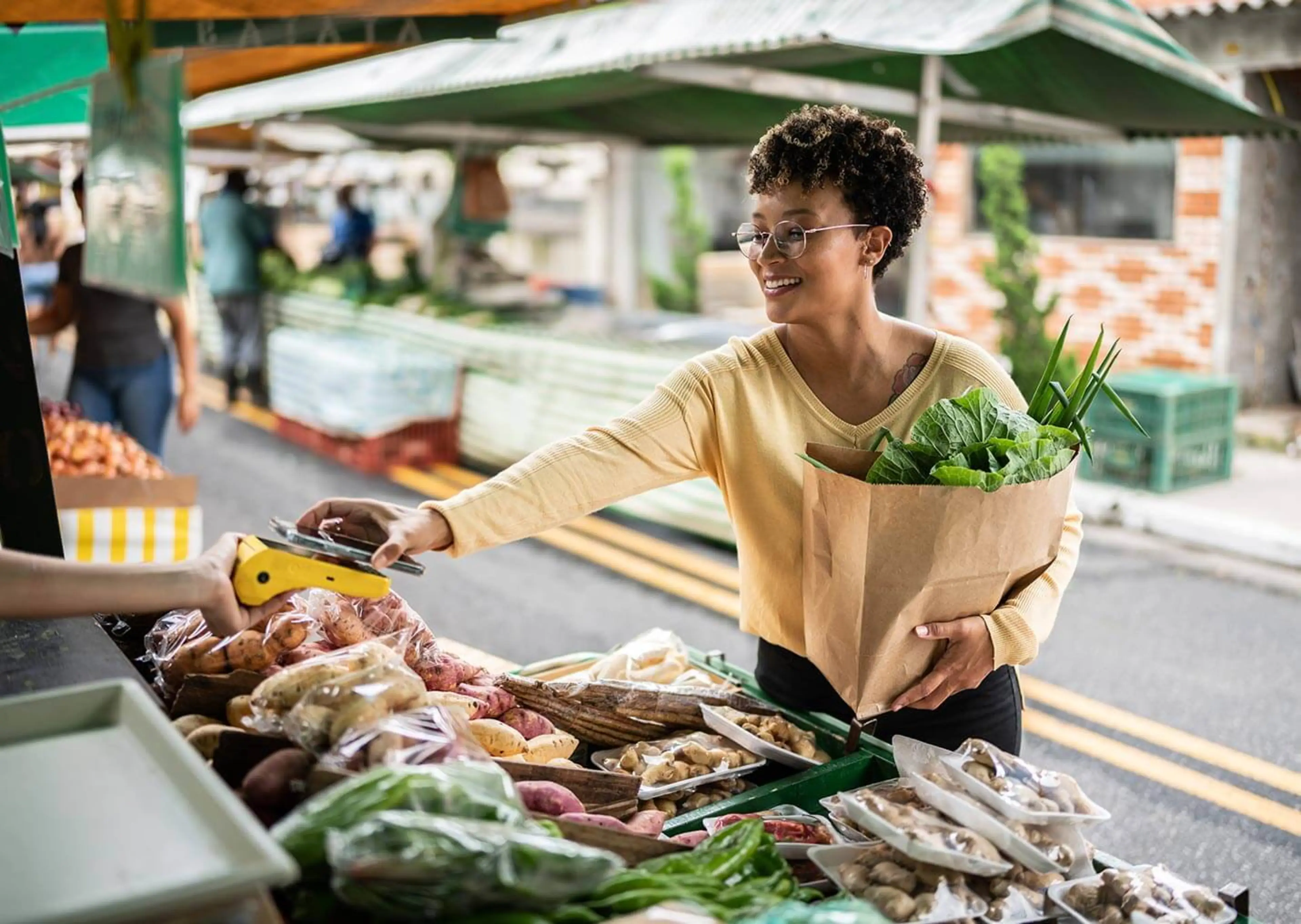 A woman is shown shopping outside at a farmers market, another popular money saving hack.