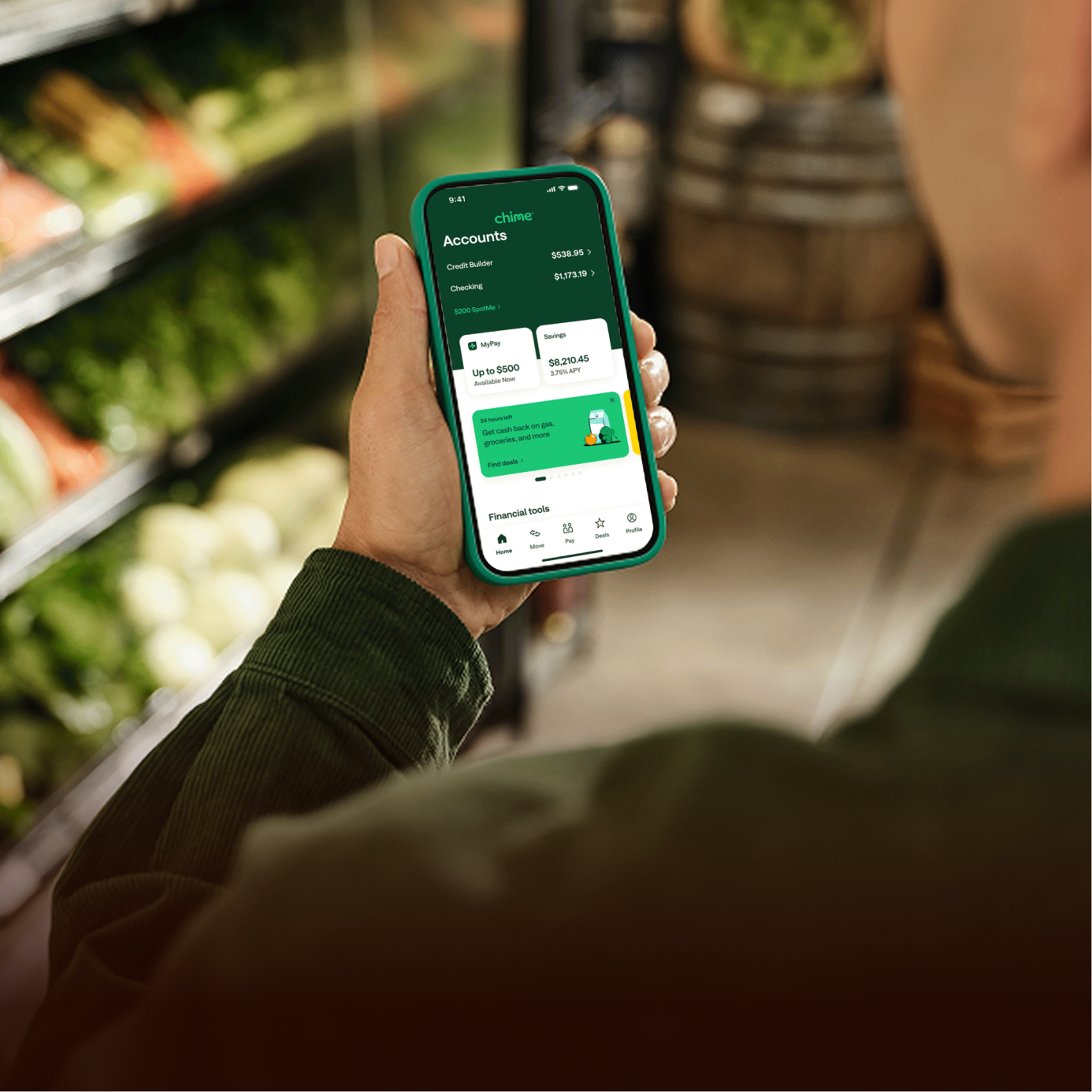 Person holding a phone with the Chime app open, showing account balances, SpotMe, MyPay and Savings in a grocery store.