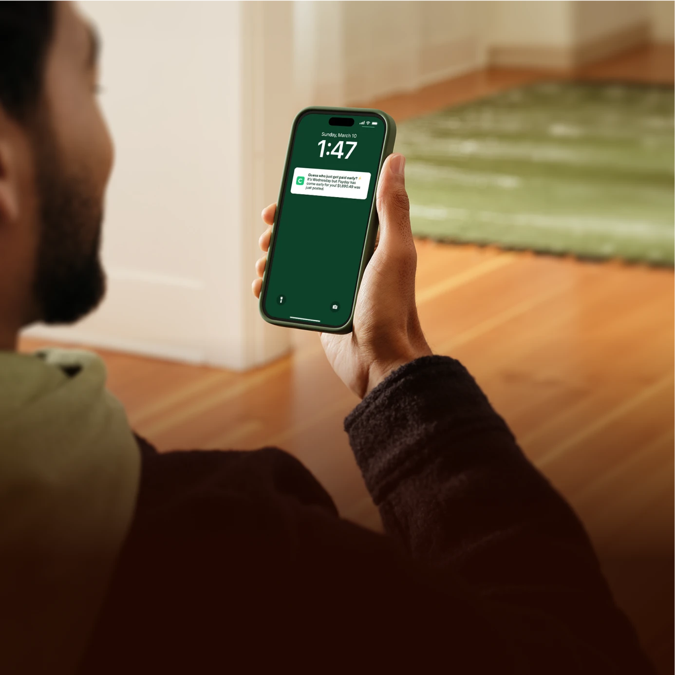 Person holding a smartphone displaying a Chime notification about early payday.