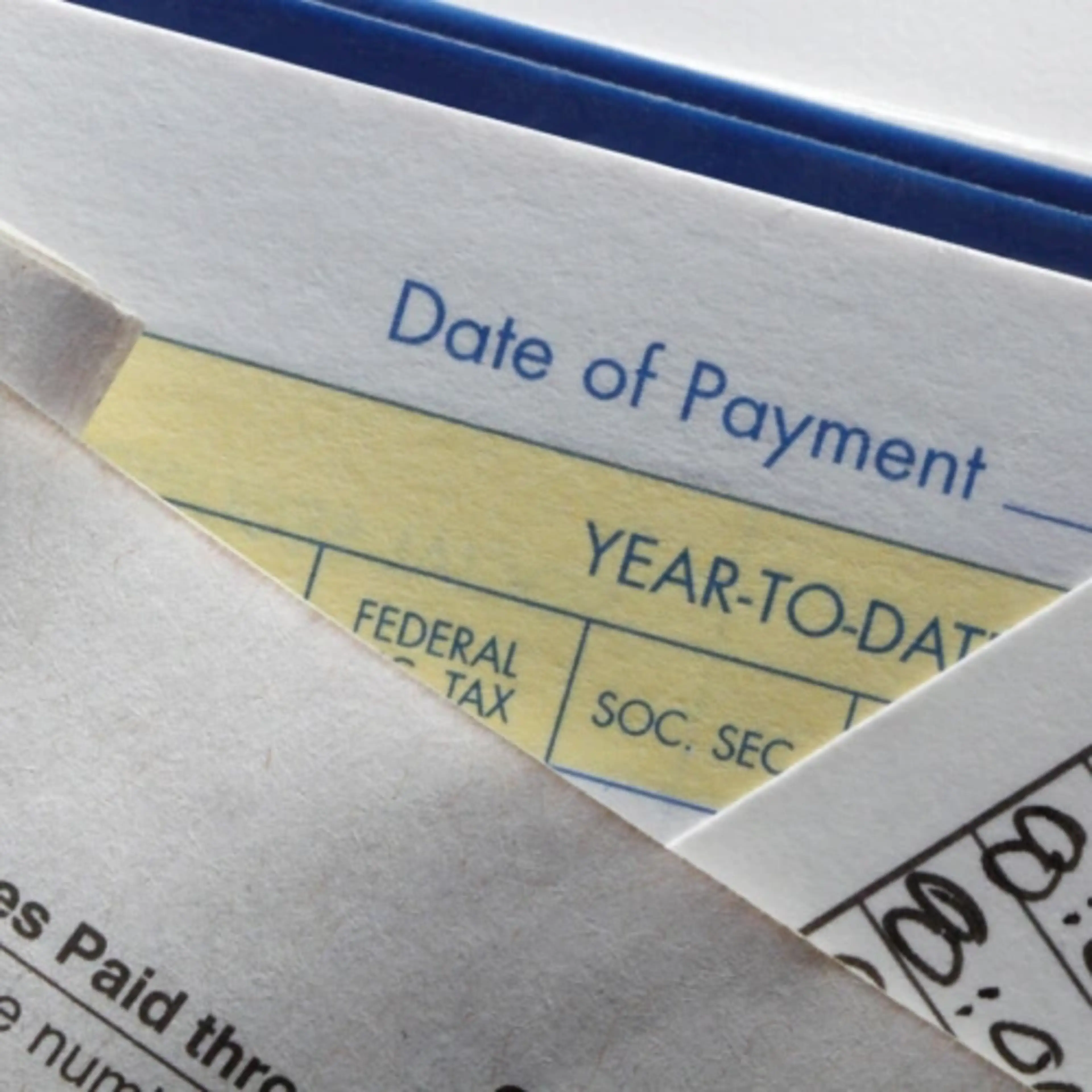 Close-up of a partially visible paycheck, showing date of payment and tax details.