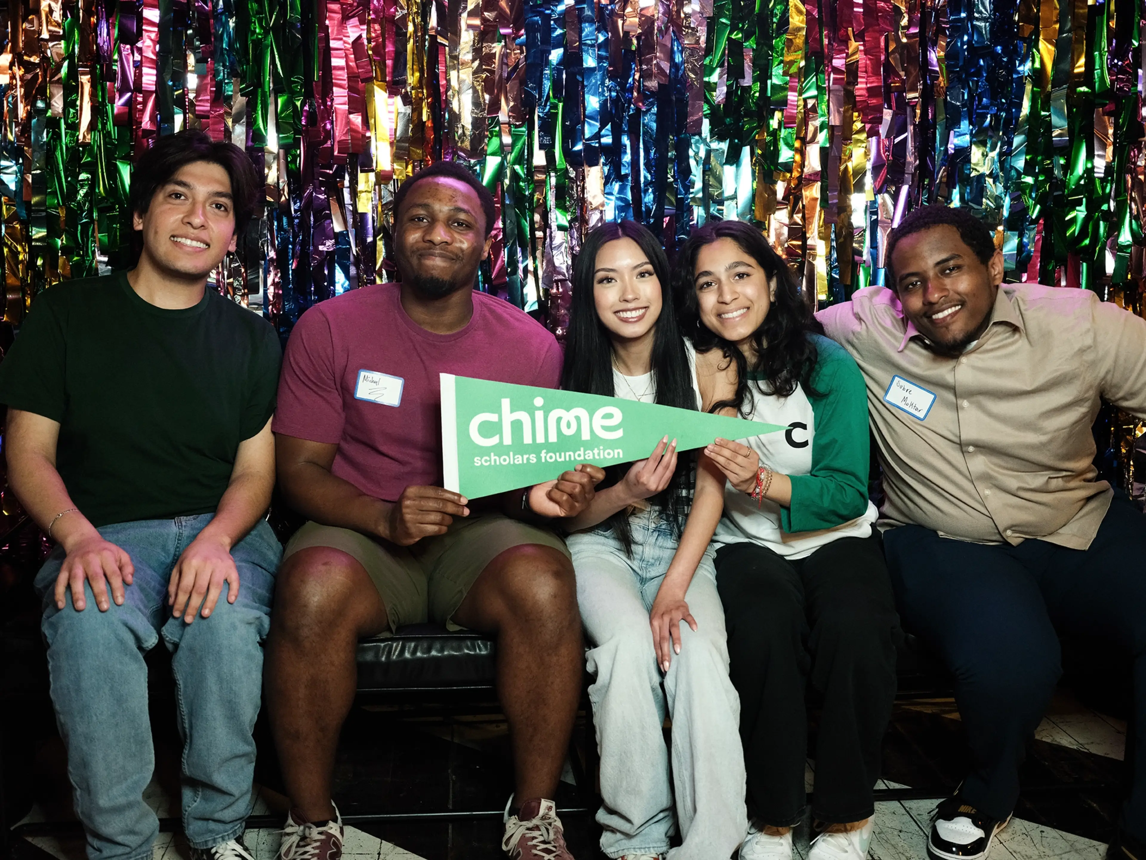 Chime Scholars Foundation students sitting on with Chime pennant and celebrating.