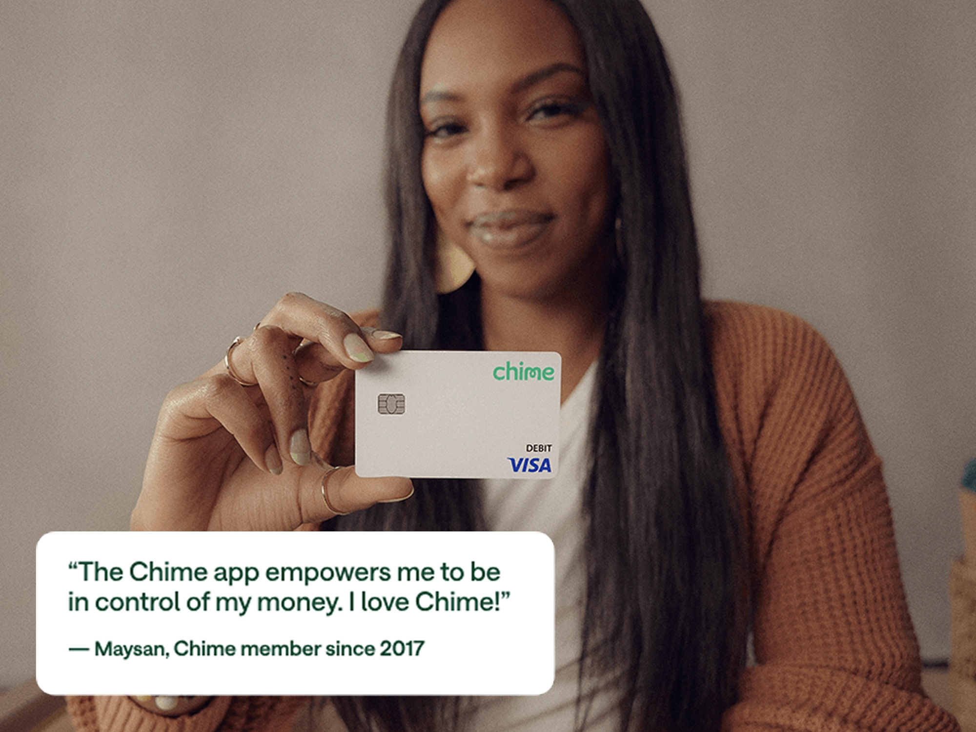 Person in orange cardigan holding a white Chime debit card with testimonial quote from Maysan, member since 2017.