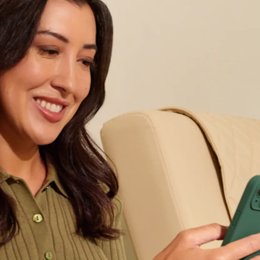 A person sitting on their couch looking at their phone.