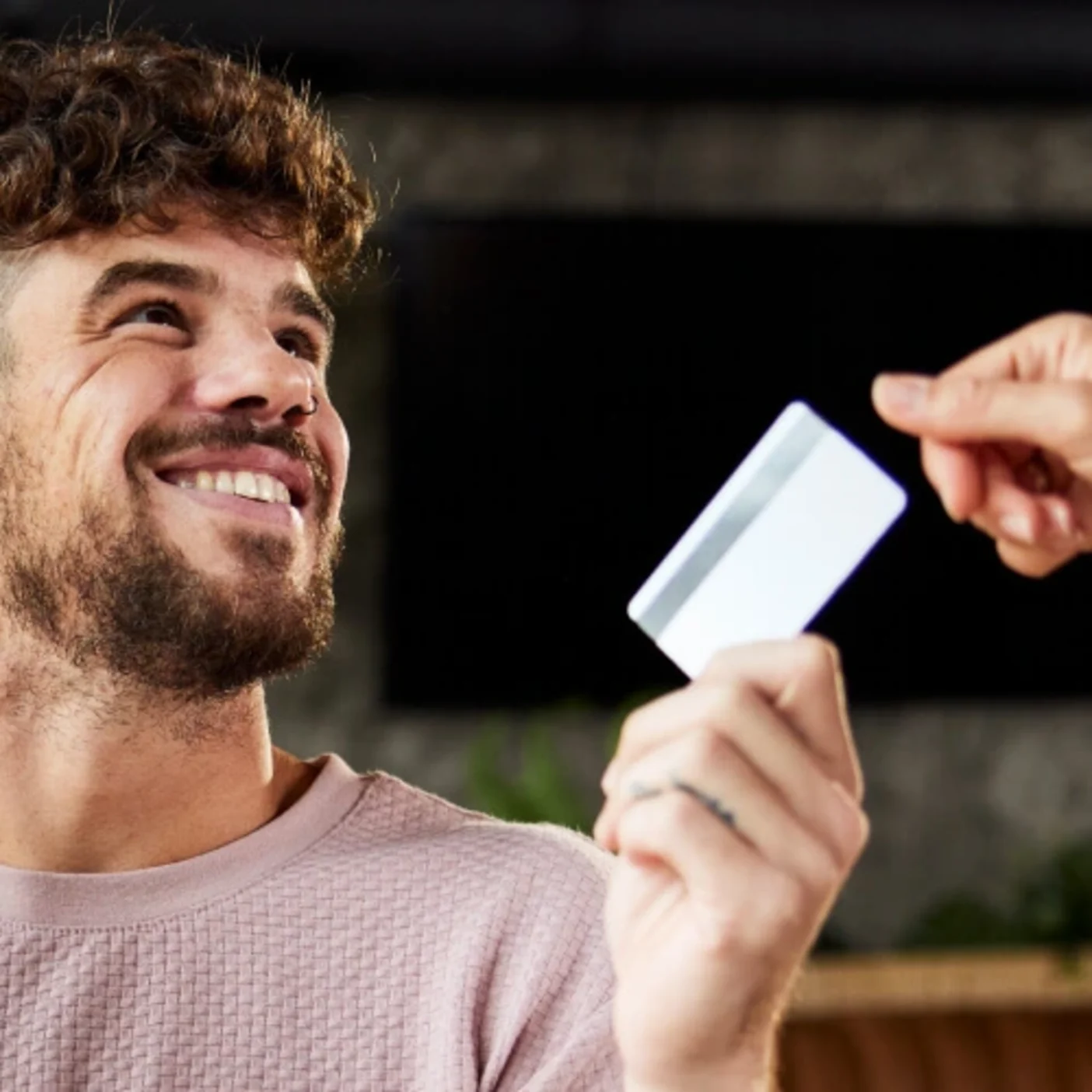 A guy handing over a debit card to another person.