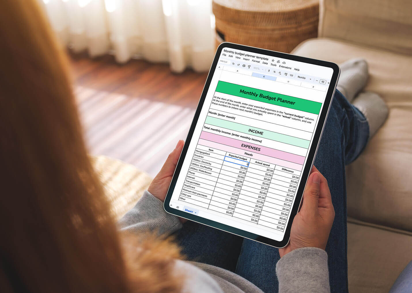 A woman holds an iPad that shows a downloadable monthly budget spreadsheet.